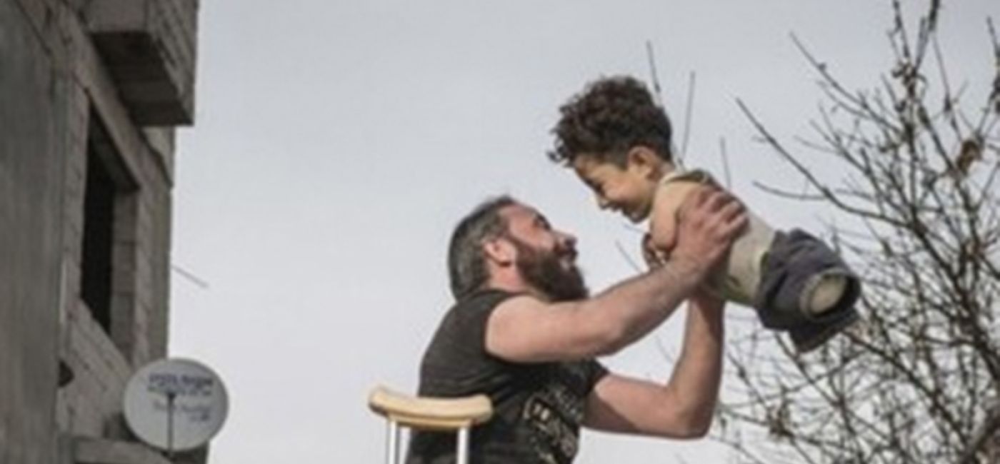 Lo scatto del fotografo turco Mehmet Aslan ritrae papà Munzir al-Nazzal mentre protende in aria il suo piccolo Mustafa: la gioia in Siria nonostante la guerra e le ferite